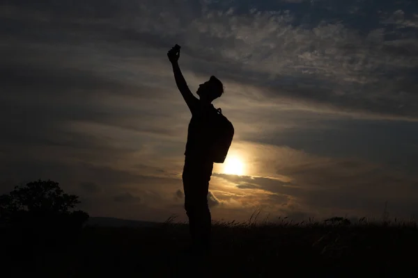 Un hombre de pie en una colina mirando enlace en el fondo de una hermosa puesta de sol —  Fotos de Stock