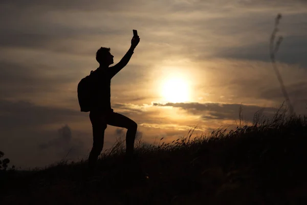 Ένας άνθρωπος στέκεται σε ένα λόφο αναζητούν σύνδεσμο στο φόντο ενός όμορφου ηλιοβασιλέματος — Φωτογραφία Αρχείου