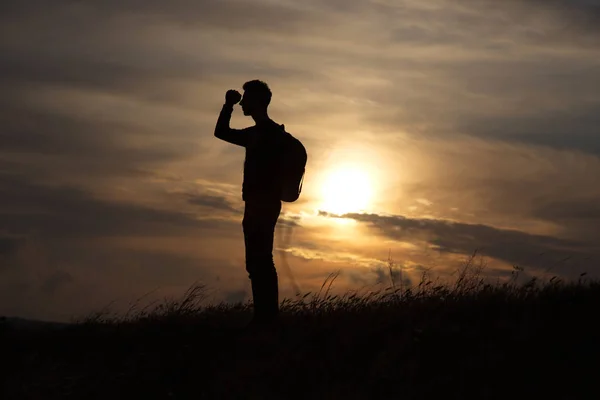 Muž proti moři stojí na vrcholu hory a dívá se do dálky — Stock fotografie