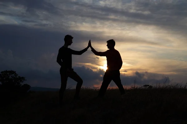 Senderistas masculinos y femeninos subiendo por el acantilado de la montaña y uno de ellos dando una mano amiga. Personas ayudando y, concepto de trabajo en equipo . —  Fotos de Stock