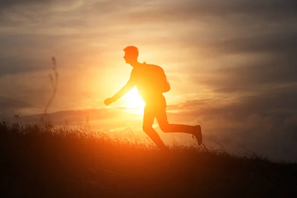 L'uomo corre direttamente su una collina contro un bel tramonto — Foto Stock