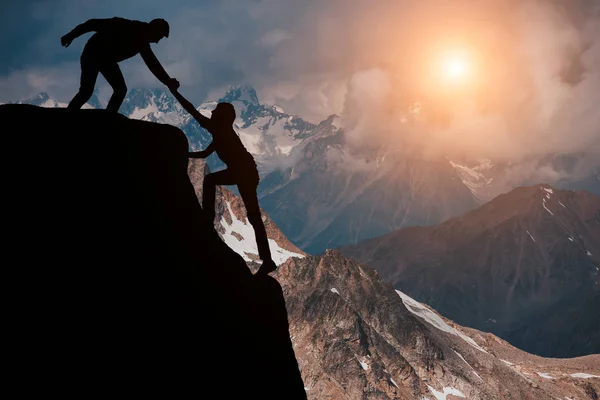 Senderistas masculinos y femeninos subiendo por el acantilado de la montaña y uno de ellos dando una mano amiga. Personas ayudando y, concepto de trabajo en equipo . — Foto de Stock