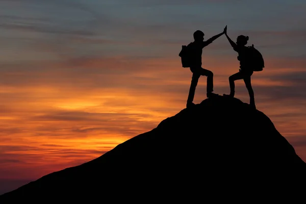 男女徒步旅行者爬上山崖，其中一人伸出援手。人们的帮助和团队精神. — 图库照片