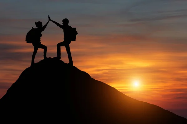 Male and female hikers climbing up mountain cliff and one of them giving helping hand. People helping and, team work concept. — Stock Photo, Image