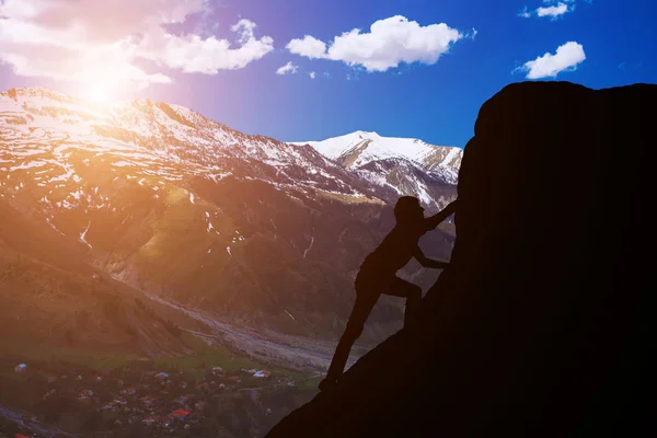 Silhueta de um homem para conquistar as montanhas de pico contra um belo pôr do sol — Fotografia de Stock