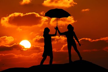 iki kız bir güzel gün batımı holding şemsiyesi arka plan üzerine siluet