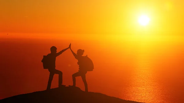 Male and female hikers climbing up mountain cliff and one of them giving helping hand. People helping and, team work concept. — Stock Photo, Image