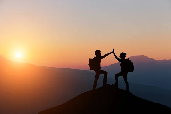 Manliga och kvinnliga vandrare klättrar uppför bergsbranten och en av dem ger hjälpande hand. Människor som hjälper och, team arbetskoncept. — Stockfoto