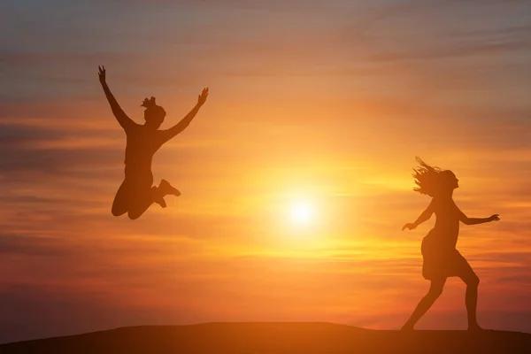 Dvě krásná silueta dívka, která skočila při západu slunce — Stock fotografie