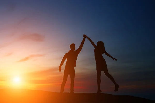 Silhouet jongen en meisje op een mooie zonsondergang hand in hand — Stockfoto