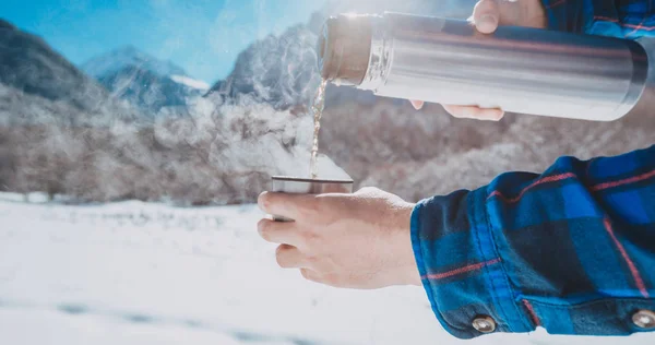 Hombre sosteniendo un termo en una montaña nevada —  Fotos de Stock