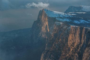 Kış günbatımı kar alan Kırım orman ve tepeler gri gökyüzü altında arka plan üzerinde soğuk çam ağaçları ile dağ yamacı üzerine.