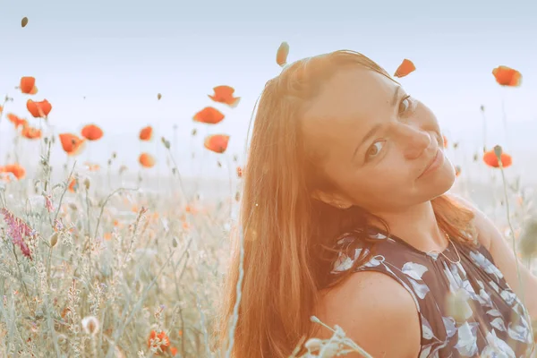 Όμορφο κορίτσι σε ένα χωράφι με παπαρούνες το ηλιοβασίλεμα. έννοια της ελευθερίας — Φωτογραφία Αρχείου