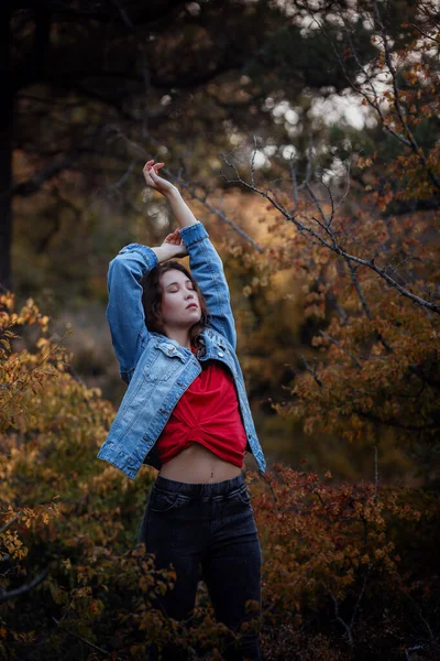A rapariga viaja na floresta das montanhas. Uma rapariga com um casaco de ganga e uma t-shirt vermelha. Montanhas no outono — Fotografia de Stock