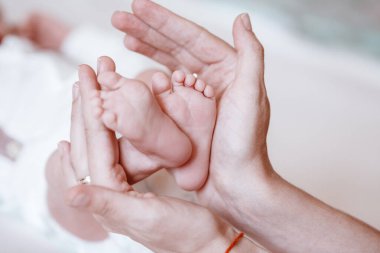 Yeni doğmuş bebeğin ayakları kadın ellerinde, yakın plan..