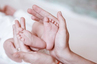Yeni doğmuş bebeğin ayakları kadın ellerinde, yakın plan..