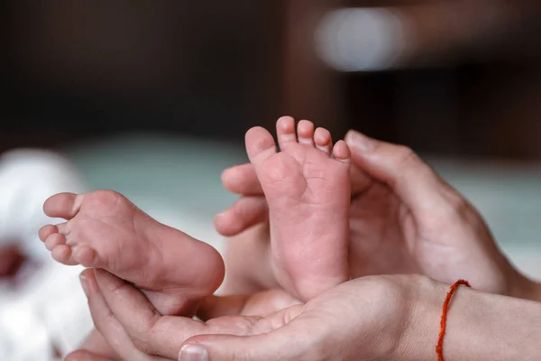 Pasgeboren baby 's voeten op vrouwelijke handen closeup. — Stockfoto