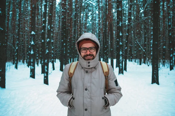 Giovane uomo in piedi nella foresta innevata invernale — Foto Stock