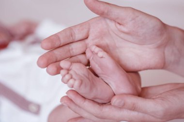 Yeni doğmuş bebeğin ayakları kadın ellerinde, yakın plan..