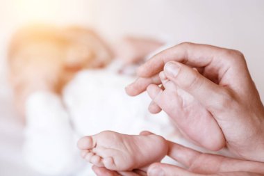 Yeni doğmuş bebeğin ayakları kadın ellerinde, yakın plan..