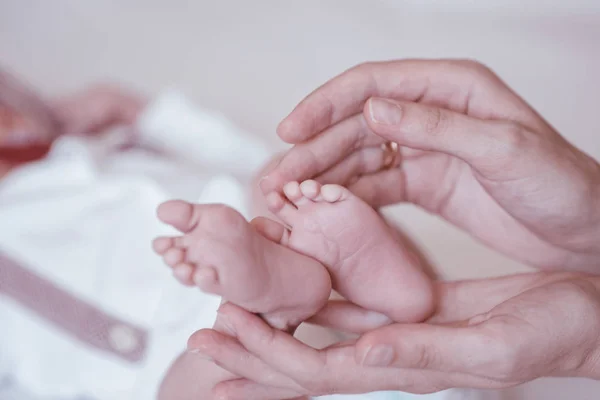 Pasgeboren baby 's voeten op vrouwelijke handen closeup. — Stockfoto