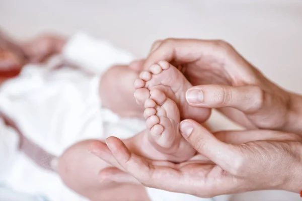 Pasgeboren baby 's voeten op vrouwelijke handen closeup. — Stockfoto