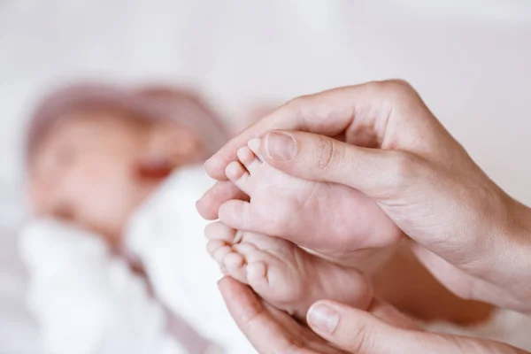 Newborn Baby's feet on female hands closeup. — Stockfoto