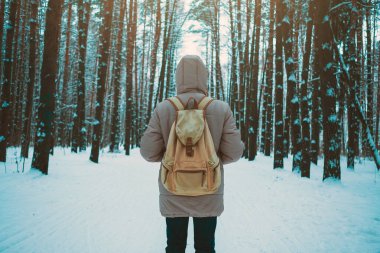 Genç adam kışın karlı ormanında