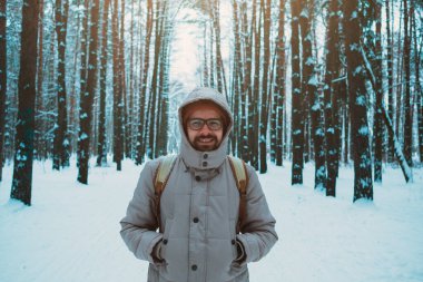 Genç adam kışın karlı ormanında