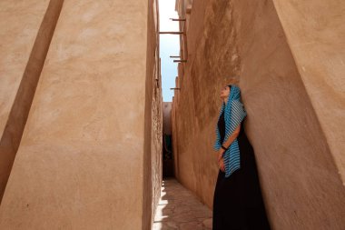 Woman walking in old Dubai city, UAE. clipart