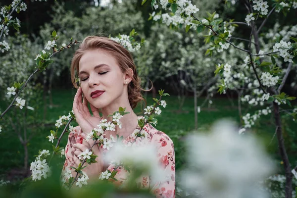 Mladá krásná žena v třešňově kvetoucí zahradě. — Stock fotografie