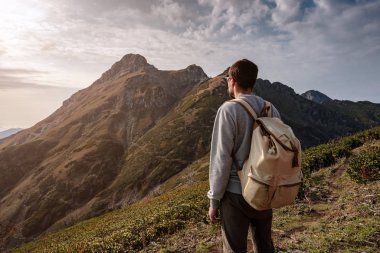 Genç adam uçurumun tepesinde duruyor.