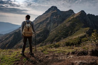 Genç adam uçurumun tepesinde duruyor.