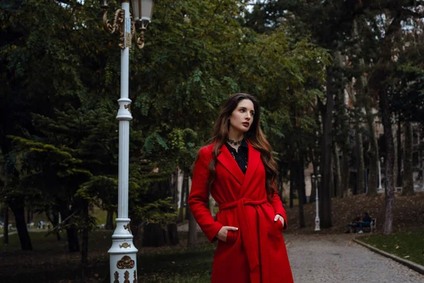 Beautiful young woman in red coat is enjoying autumn park. — 스톡 사진