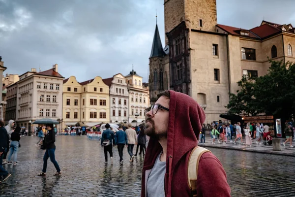 Egy férfi hátizsákkal és piros kapucnis pulóverben meglepetten néz a — Stock Fotó