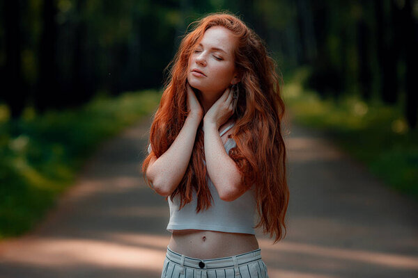 Ginger charming woman young beautiful forest green. Caucasian girl relaxing and enjoying life on nature outdoors.