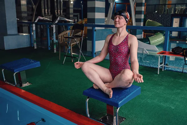 Happy muscular swimming woman wearing glasses and cap at swim pool and represent health and fit concept, idea of sport, healthy lifestyle and leisure. girl meditates and regains strength after a swim