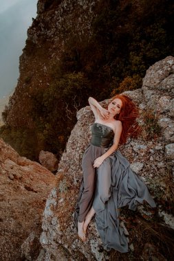 Güzel, öfkeli İskandinav savaşçı, gri elbiseli, metal zırhlı, kızıl saçlı kadın. Kadın bir Viking. Fantezi. Kitap Kapağı