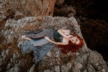 Güzel, öfkeli İskandinav savaşçı, gri elbiseli, metal zırhlı, kızıl saçlı kadın. Kadın bir Viking. Fantezi. Kitap Kapağı