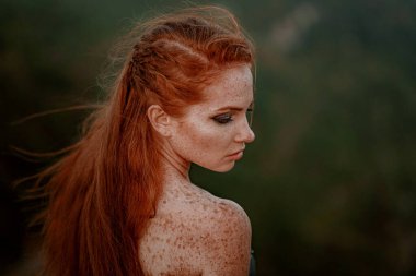 Güzel, öfkeli İskandinav savaşçı, gri elbiseli, metal zırhlı, kızıl saçlı kadın. Kadın bir Viking. Fantezi. Kitap kapağı. Yakın plan portre. Sinematik görünüm