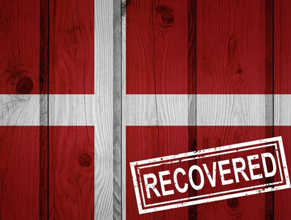 flag of Denmark that survived or recovered from the infections of corona virus epidemic or coronavirus. Grunge flag with stamp Recovered