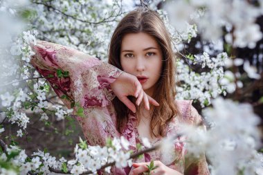 Çiçek açan bahçedeki genç Asyalı kadın. Havalı sıradan bir kadının romantik görüntüsü, modaya uygun ipek bir bluz. Olumlu ruh hali. Cheery Blossom Japonya 'da çiçek açmış..