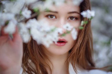 Çiçek açan bahçedeki genç Asyalı kadın. Havalı sıradan bir kadının romantik görüntüsü, modaya uygun ipek bir bluz. Olumlu ruh hali. Cheery Blossom Japonya 'da çiçek açmış..
