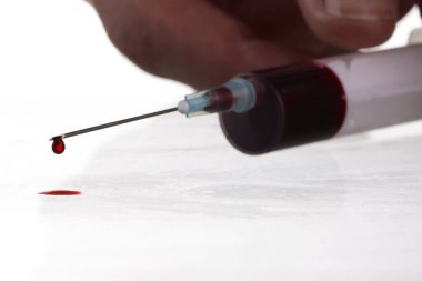 Erkek eli beyaz arka planda olan şırıngadaki kan damlasının makro görüntüsü. Kan kimyası. Virüsler için kan testi.