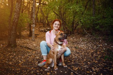 Kızıl saçlı kadın ve köpeği yürürken iyi eğlenceler. Fikir ve konsept boş zaman, mutluluk, ilgi ve özgürlük, ormanda uzun yürüyüşler