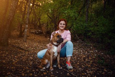 Kızıl saçlı kadın ve köpeği yürürken iyi eğlenceler. Fikir ve konsept boş zaman, mutluluk, ilgi ve özgürlük, ormanda uzun yürüyüşler