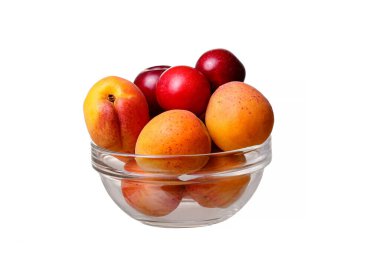 Beyaz arka planda kayısı ve erikli cam kase.