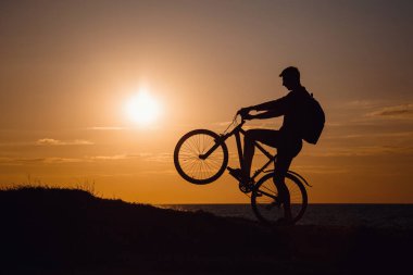 Güzel günbatımında hareket halindeki bisikletçi silueti. Sağlıklı yaşam tarzı fikri ve kavramı, sağlık ve karantina muafiyetleri için egzersiz
