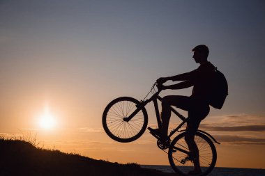 Güzel günbatımında hareket halindeki bisikletçi silueti. Sağlıklı yaşam tarzı fikri ve kavramı, sağlık ve karantina muafiyetleri için egzersiz