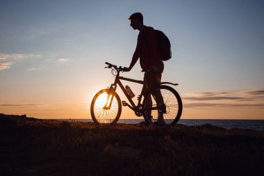 Güzel günbatımında hareket halindeki bisikletçi silueti. Sağlıklı yaşam tarzı fikri ve kavramı, sağlık ve karantina muafiyetleri için egzersiz